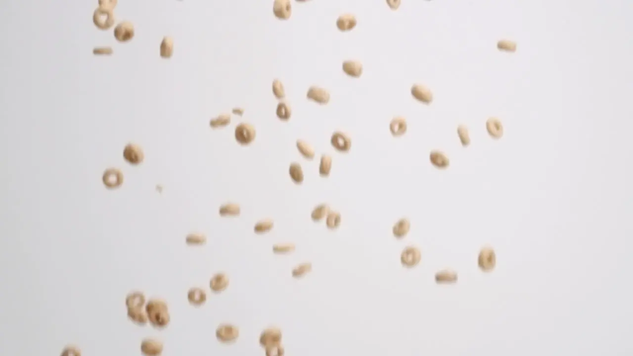 Cheerios cereal raining down on white backdrop in slow motion