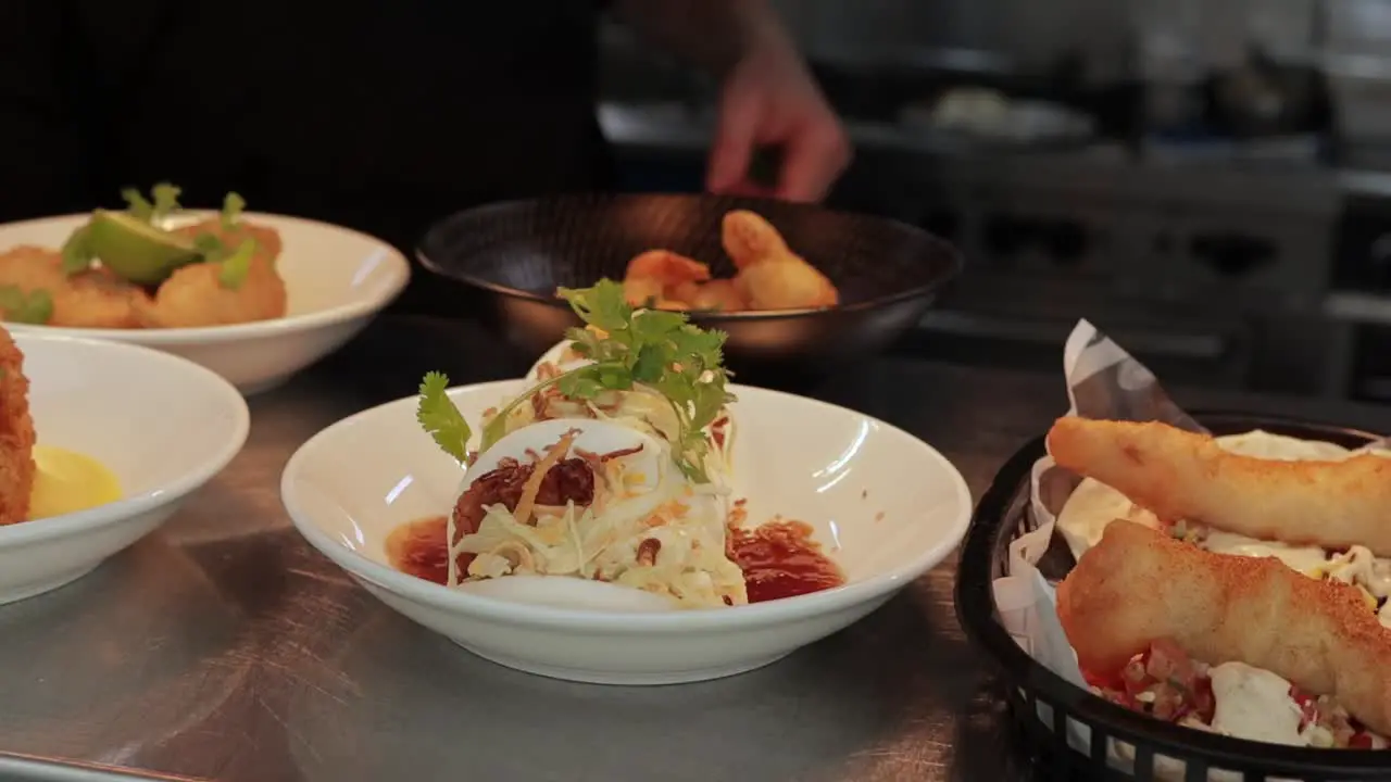 Close up shot of delicious Chinese bao buns garnished with herbs and sauce while lime is added by the chef for a delicious meal with other dishes on the side