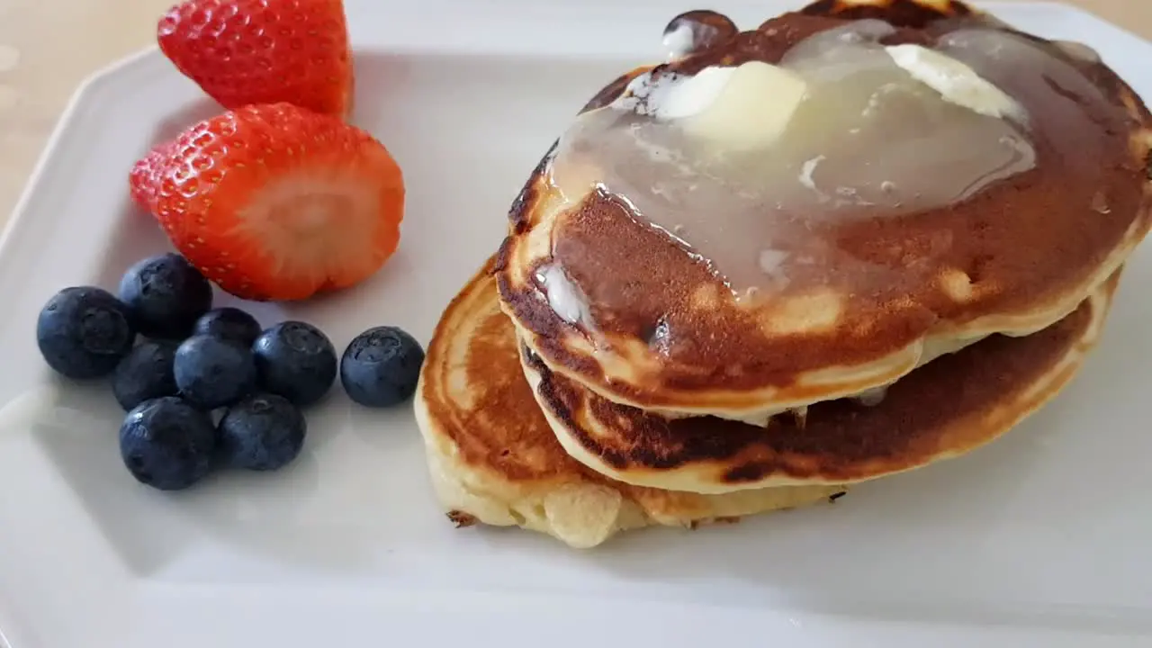 Pancakes with honey butter topping and fruit on the side