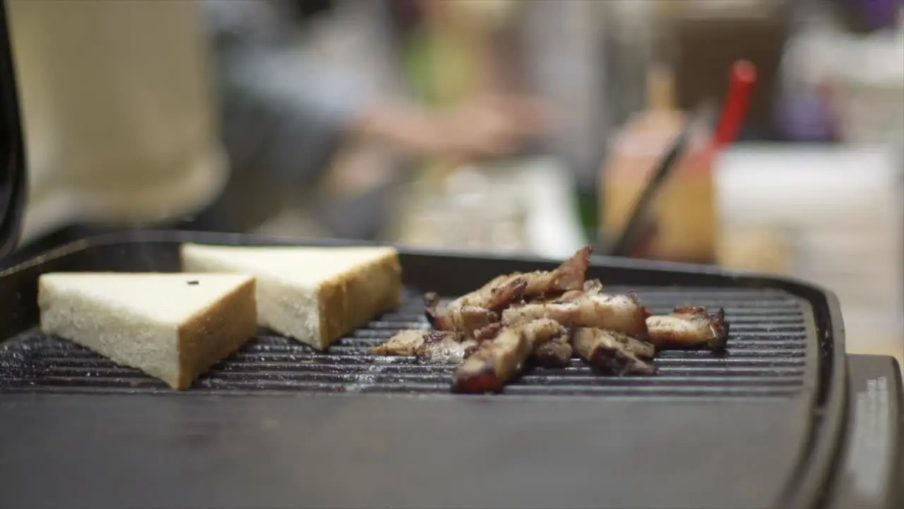 White bread placed onto barbecue grill with meat for charring toast filmed as close up shot in slow motion handheld style