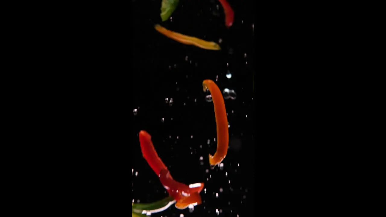 Bell peppers flying in the air splashing with water in slowmotion