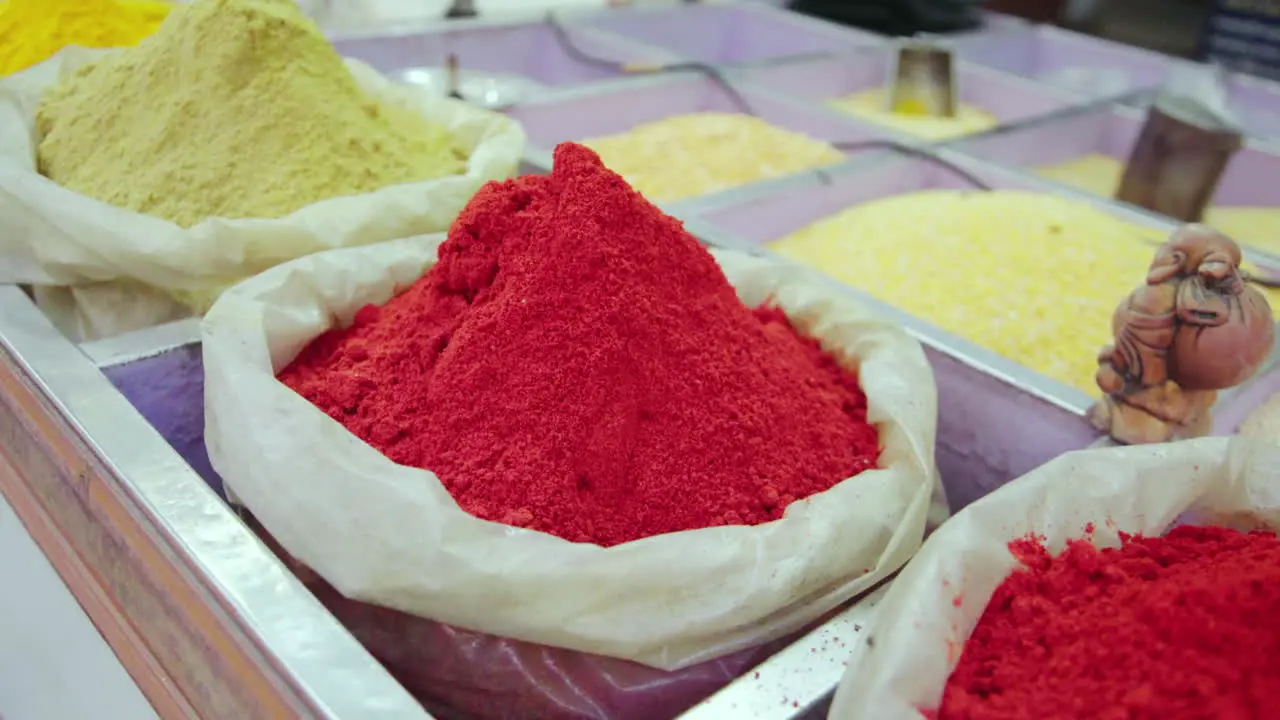 Flies buzz around bins full of spices at a market