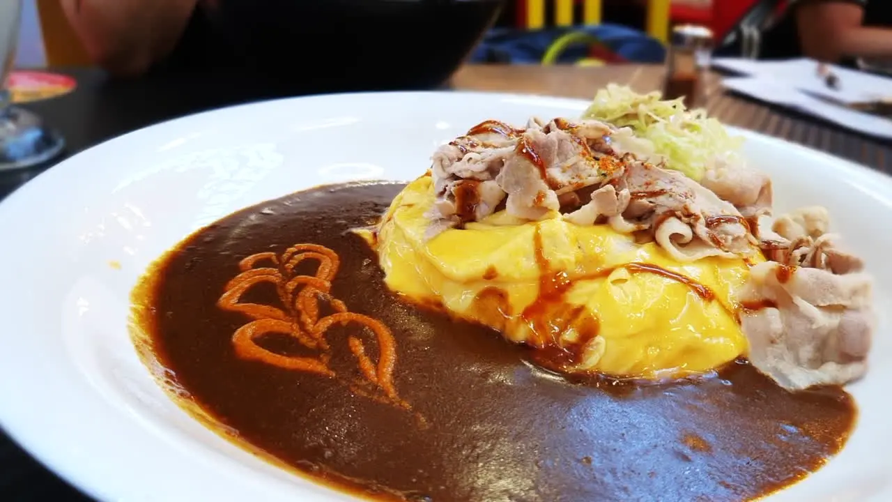 Japanese curry with pork bacon and egg omelette on top of Japanese rice in cosy restaurant