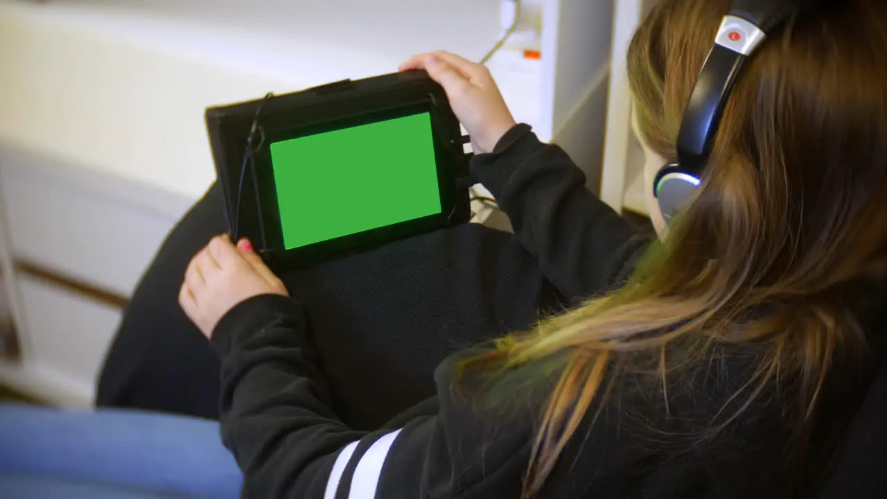 Close up of young girl sits at home using her tablet with her headphones on