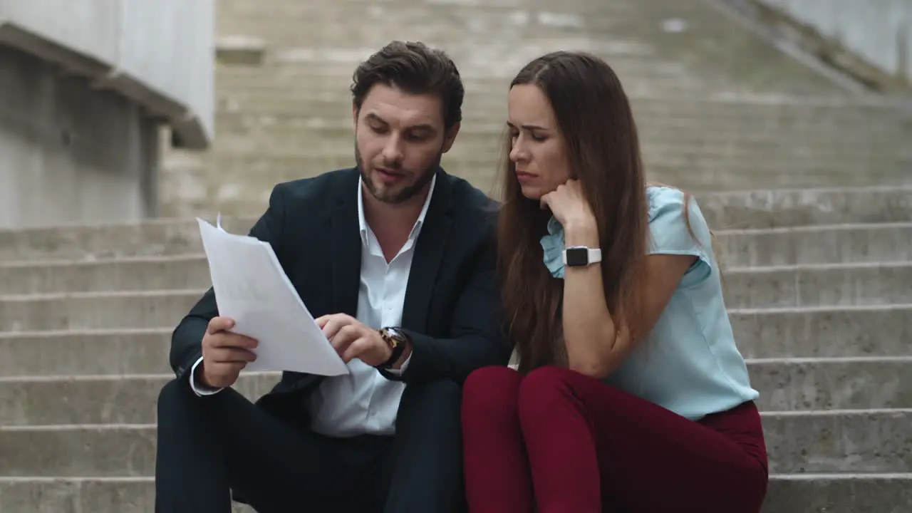 Serious business couple working with papers on stairs outdoors