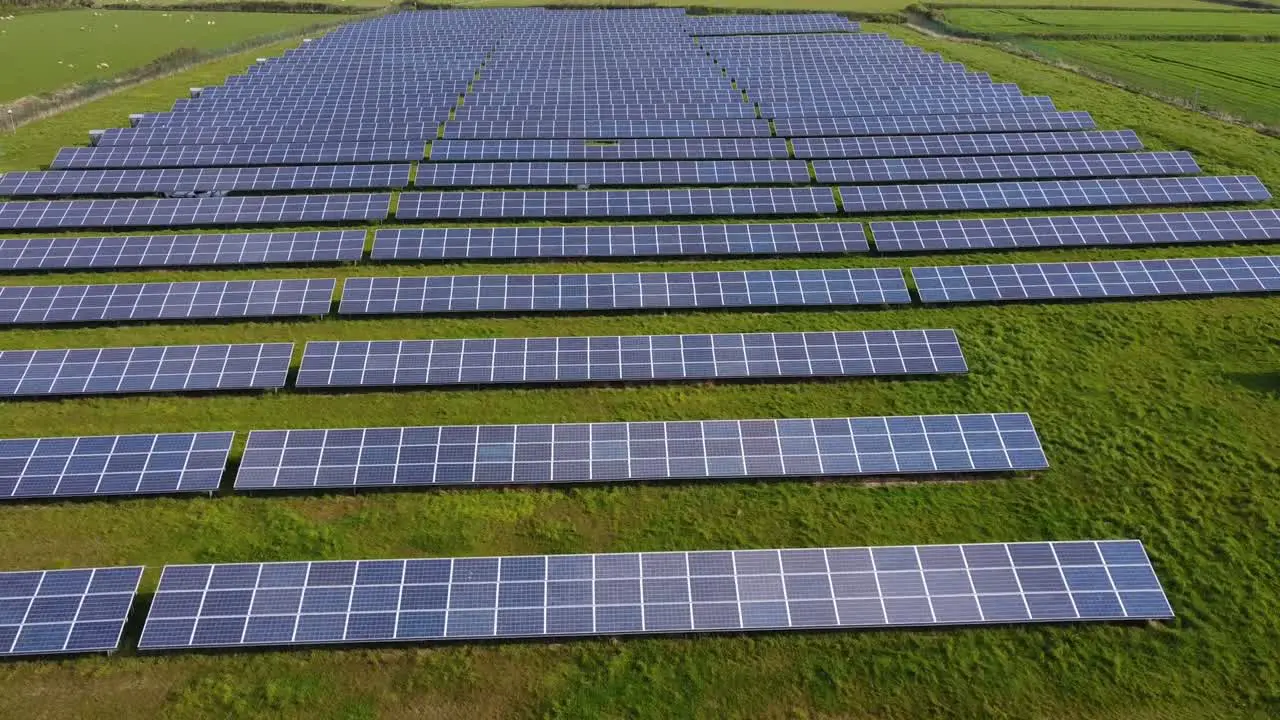 Flying over solar farm panels looking up at horizon over green field