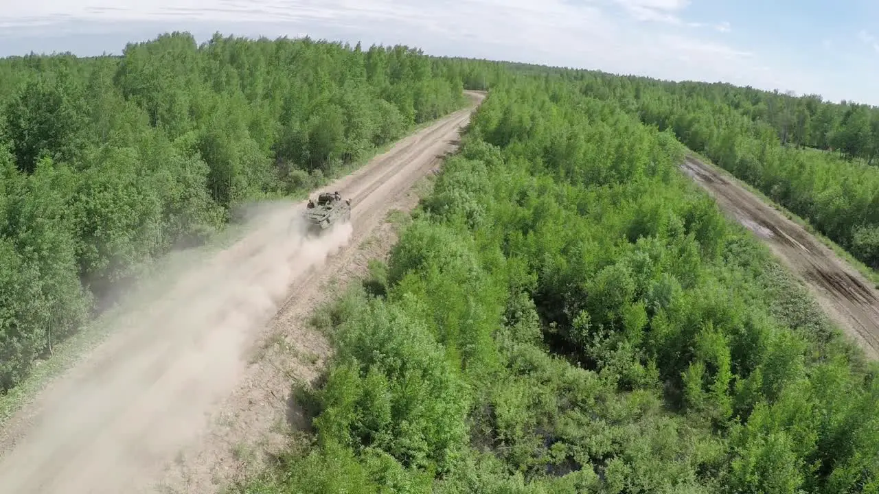 Flying over military vehicle on dirt road in woodland