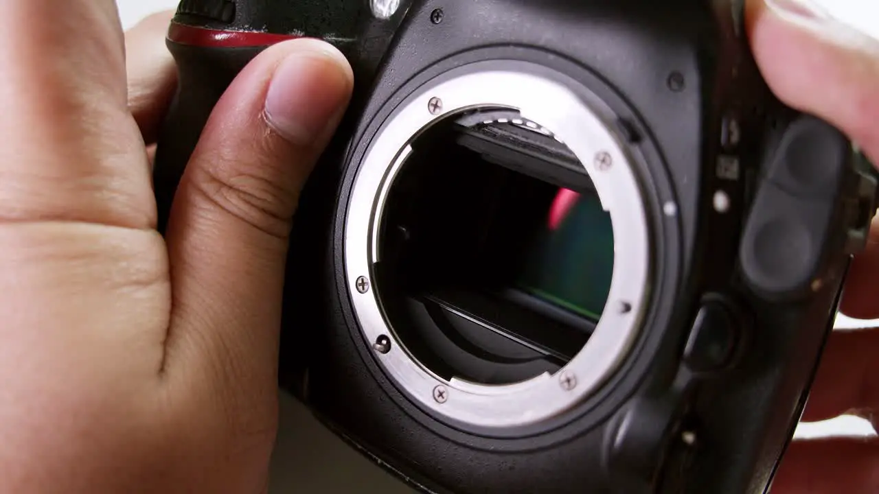 Close-up of a technician clicking the shutter and meticulously checking the sensor of a DSLR camera