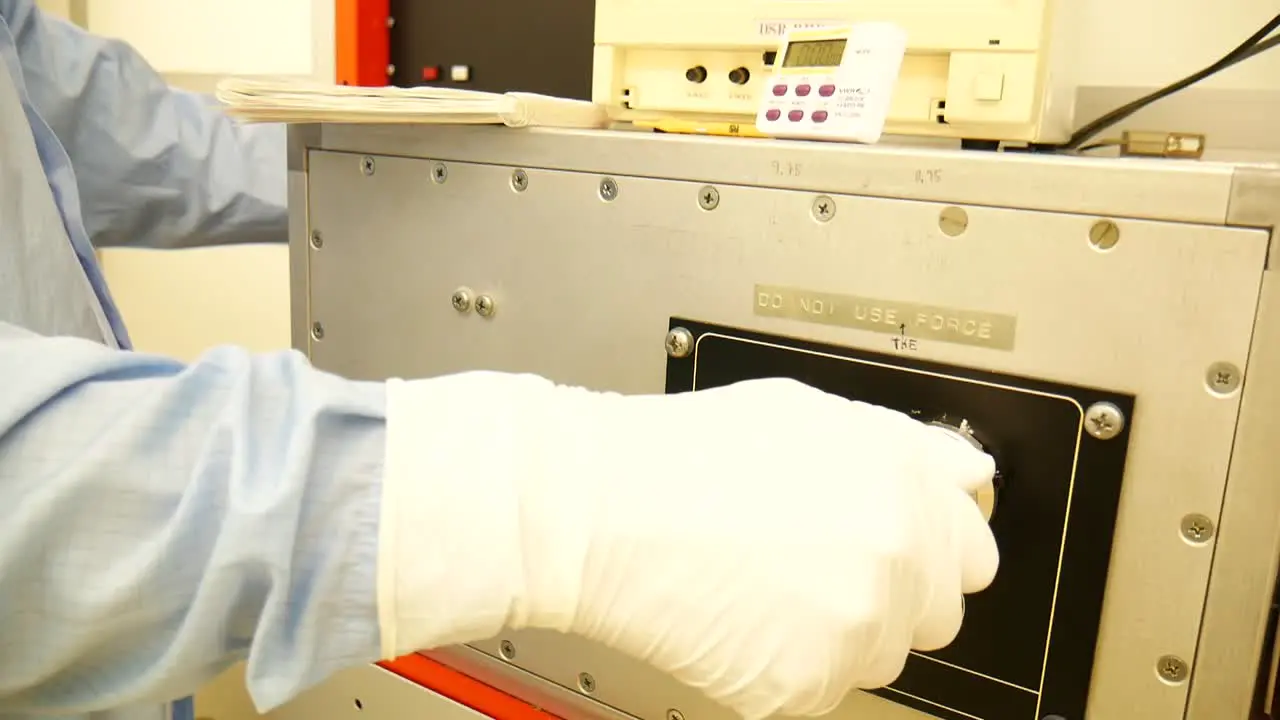 A scientist handling a big centrifuge reading the data of a big computer