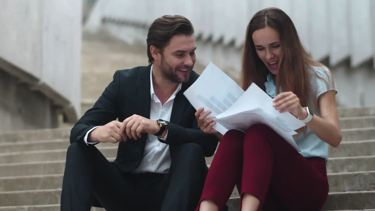 Business people reading papers outdoors Man and woman laughing on street