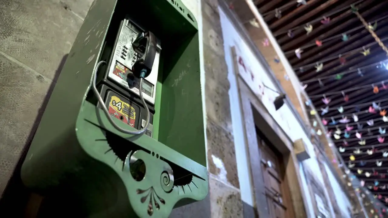 Old green payphone booth in town at night