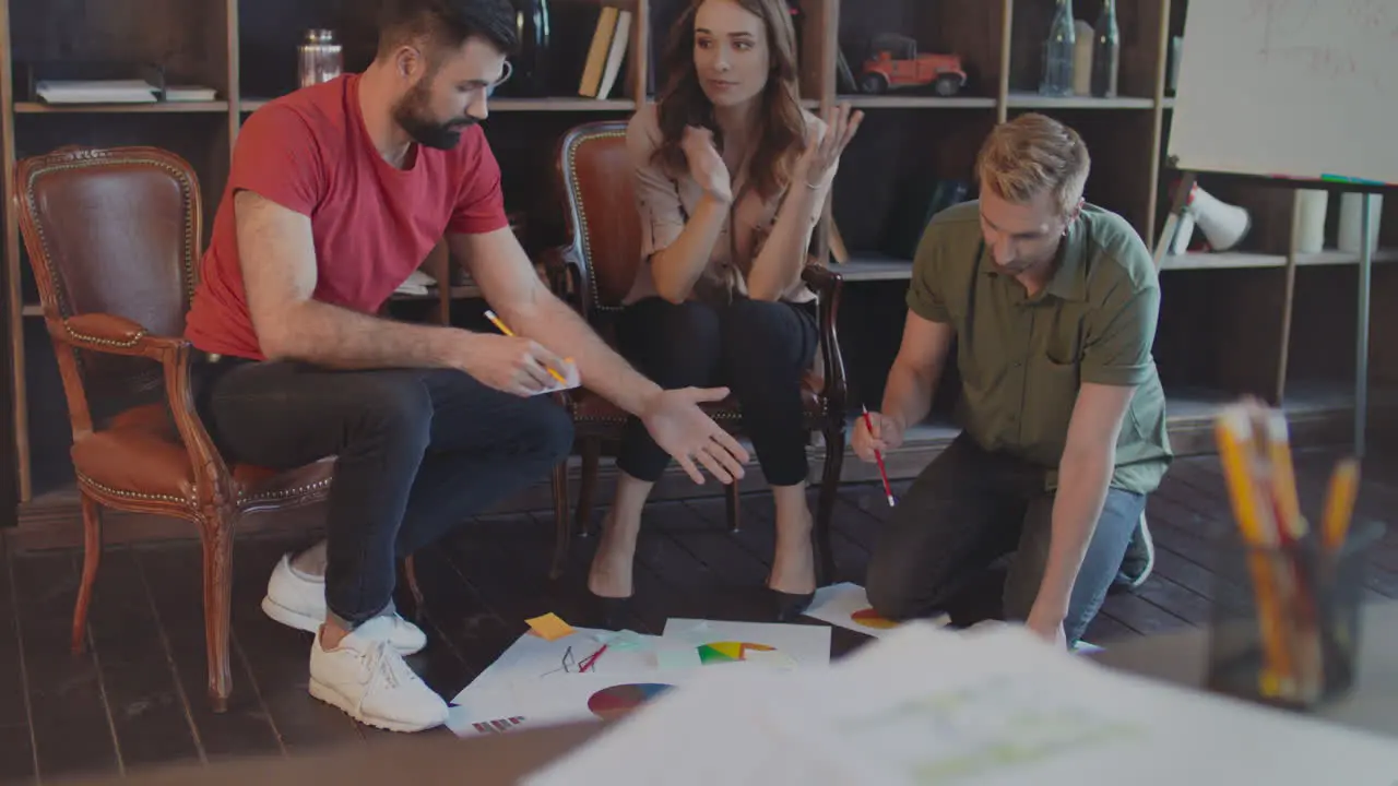 Creative team discussing business strategy documents on floor in office