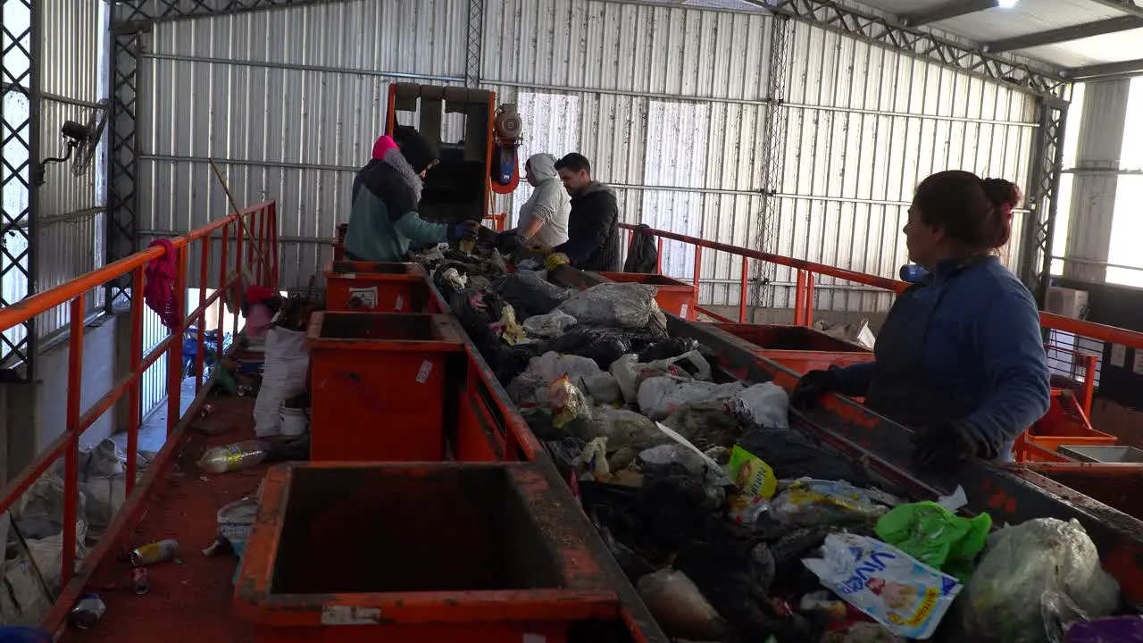 Workers inside a waste processing plant separate the waste on a conveyor belt