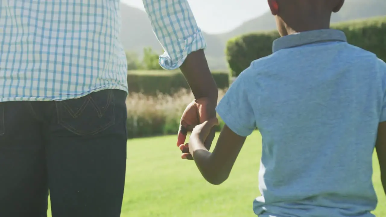 Video of happy african american father and son spending time together in the garden