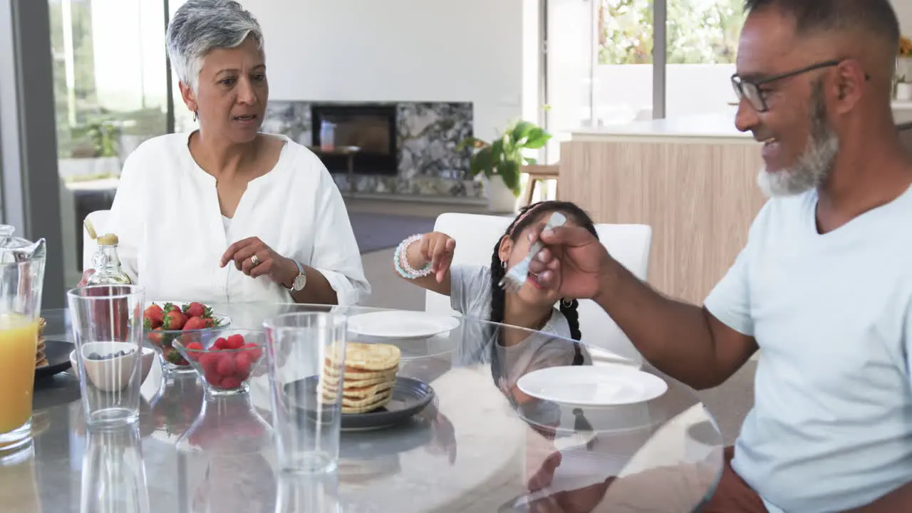 Biracial family enjoys breakfast with a child reaching for food