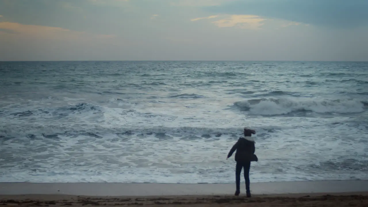 Teenage boy dancing on ocean beach at dusk