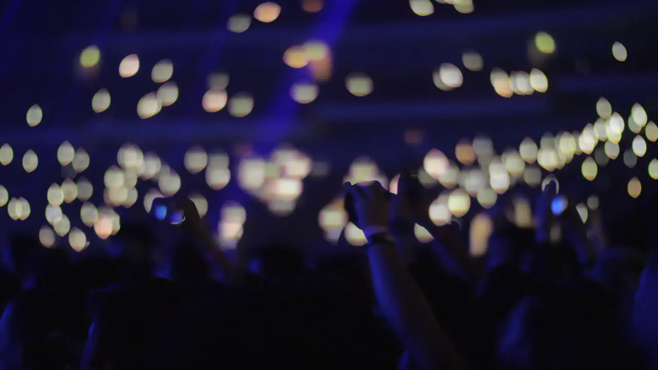 Crowd of music fans with lights in dark concert hall