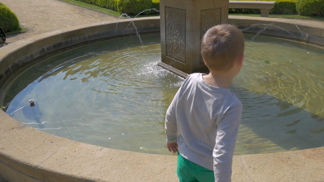 View of small boy throwing coins into the water Prague Czech Republic