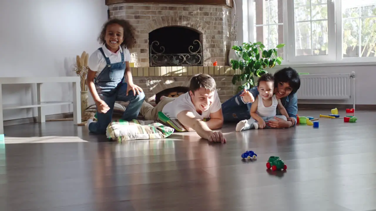 Happy Married Couple Play With Their Son With Toys On The Floor In Living Room