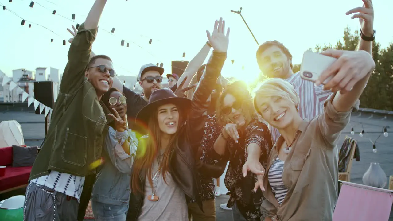 Cheerful Young Multiethnic People Having Fun And Laughing While Posing To The Smartphone Camera And Taking Selfie At The Rooftop Party