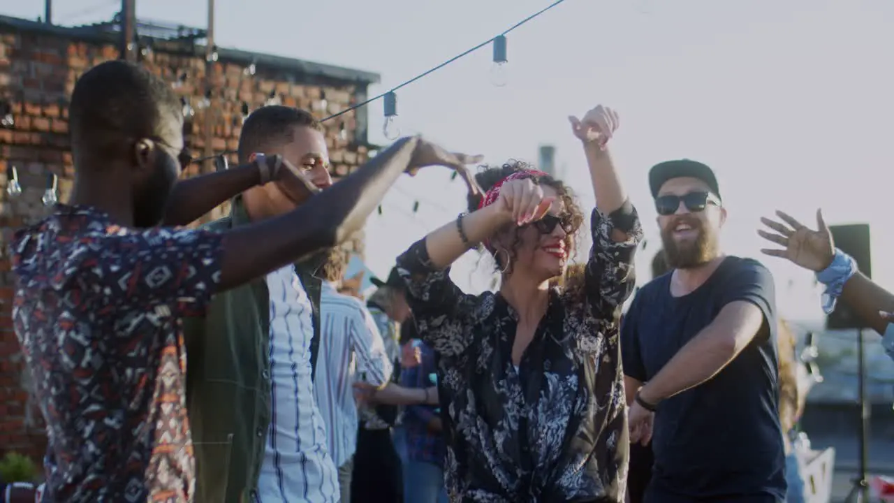 Young Stylish Woman And Happy Group Of People Dancing And Gaving Fun On The Rooftop