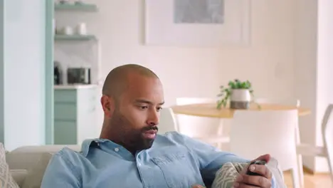 Man on living room sofa using phone on social