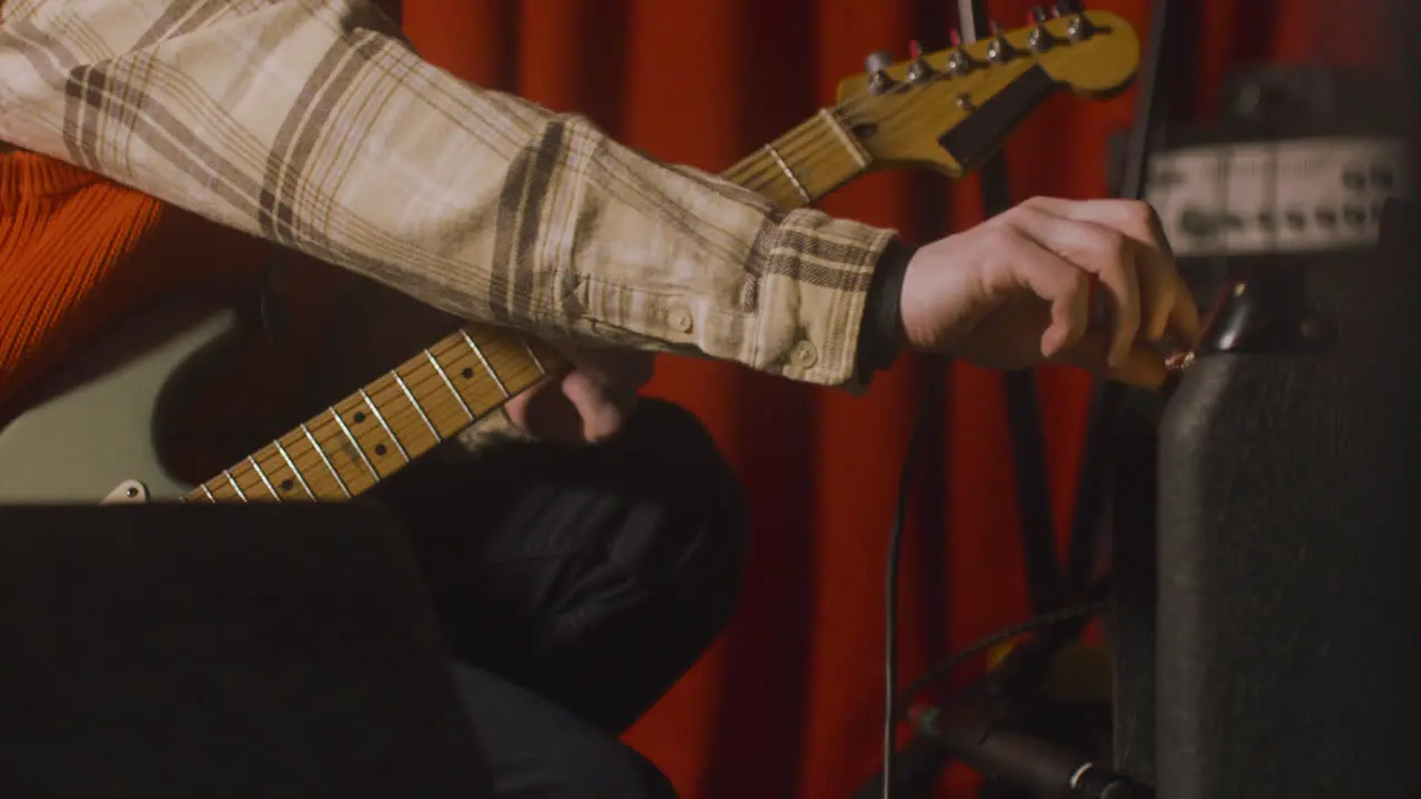 Close Up Of An Unrecognizable Musician With Electric Guitar Tuning Sound On Amplifier