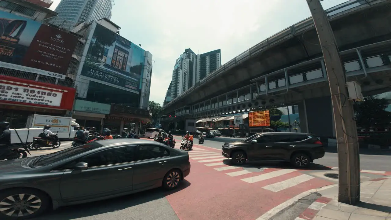 Woman crossing in the midst of the bustling city traffic in Bangkok with cars and motorcycles in motion