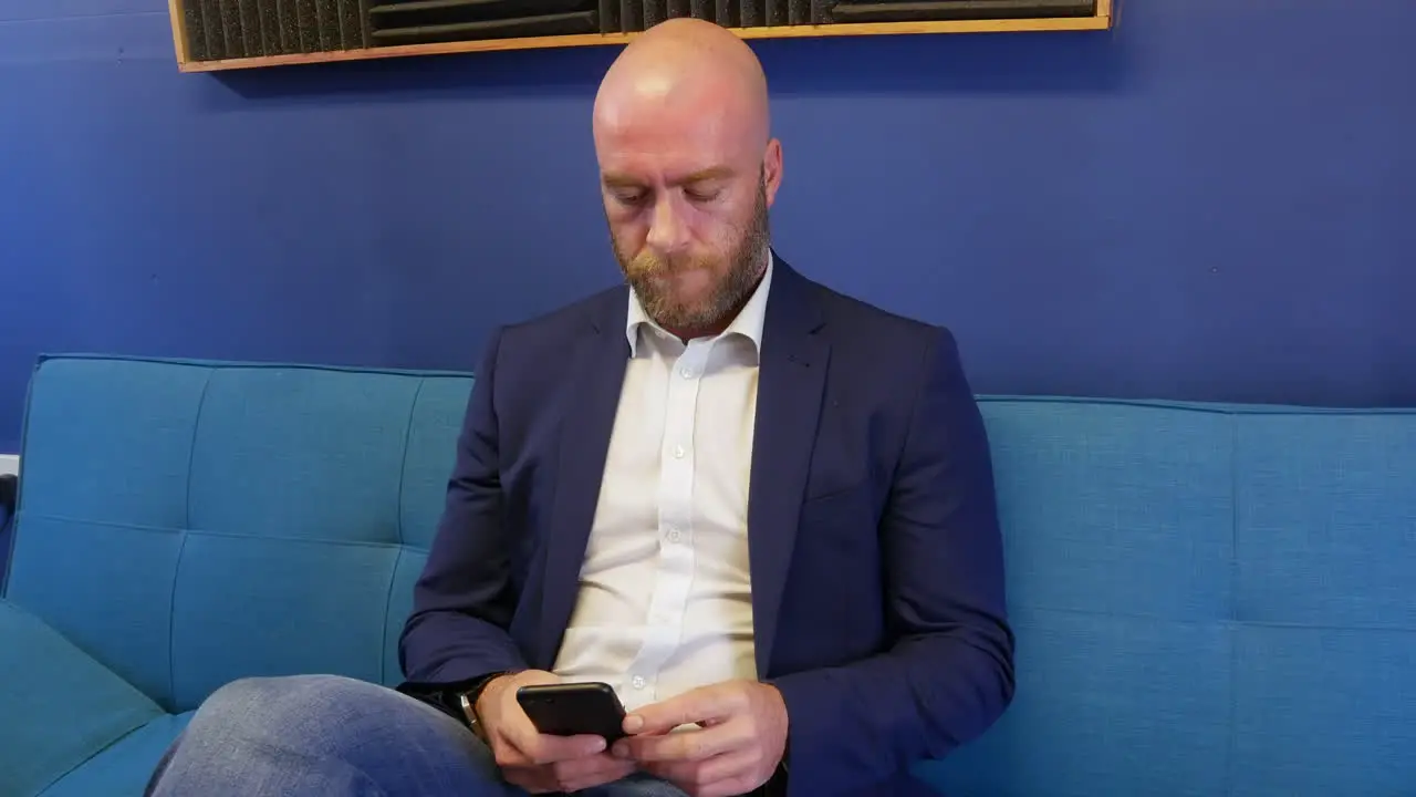 Business man looking and browsing on mobile cell phone while sitting on sofa