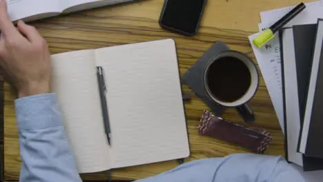 Man Reading From Textbook Whilst Leaning On His Notebook 