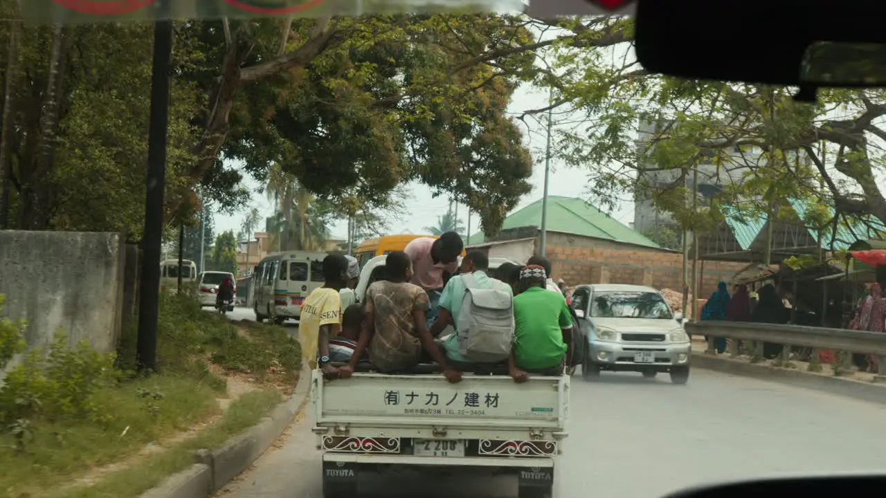 Locals ride in the back of a pickup truck in Zanzibar