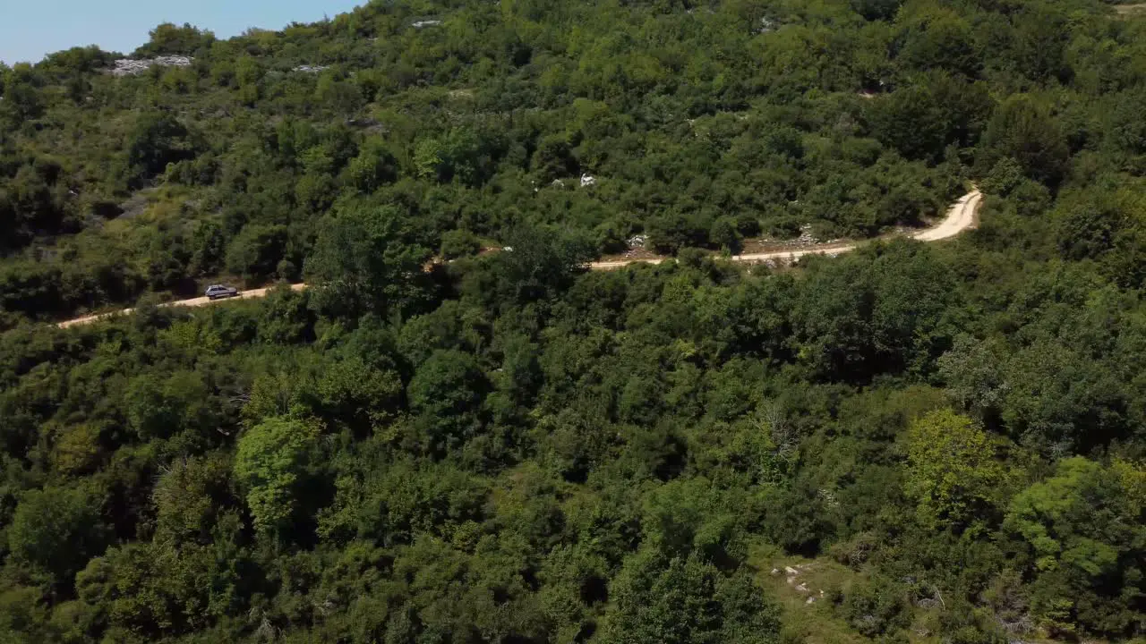 Aerial pan of 4x4 car driving off road in the forest