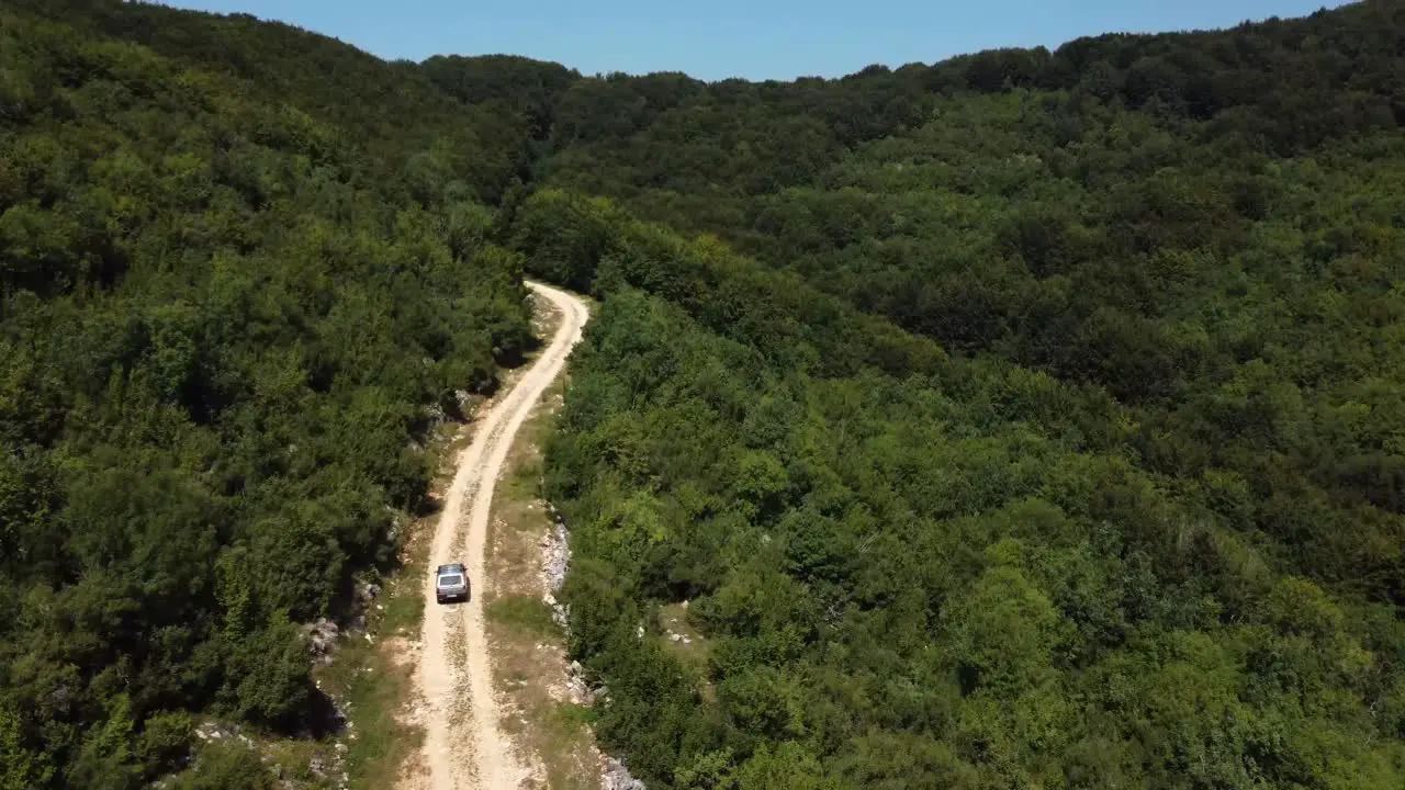 Ascending aerial of 4x4 car driving off road into the forest