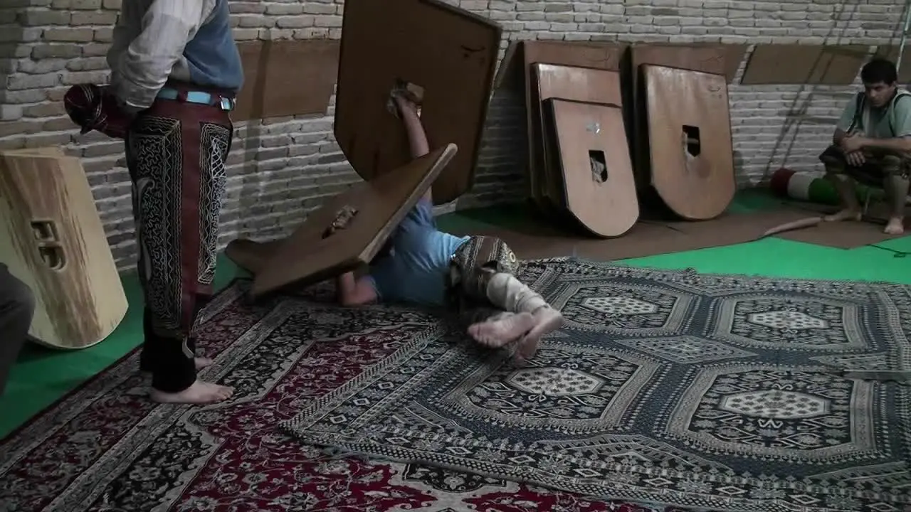 A man rolling with a wooden shield demonstrates the traditional Iranian martial art of Pahlavani