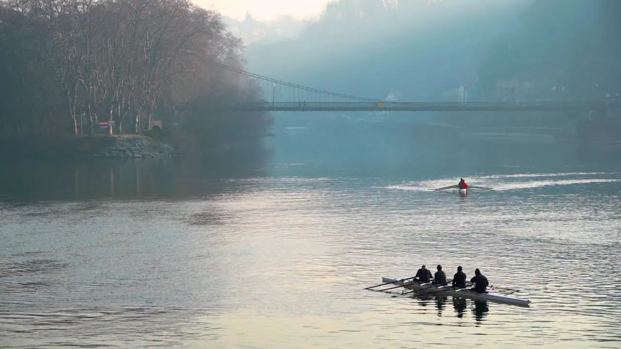 Wide shot of Rowers in front of a foggy bridge in France Lyon during the cold season