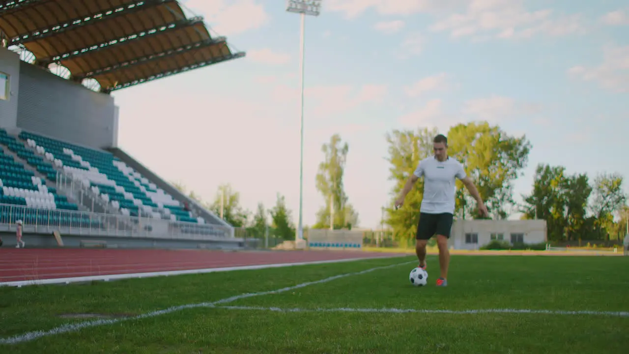 A professional football player in uniform on the football field of the stadium makes a kick at the ball after a successful run with the ball along the edge