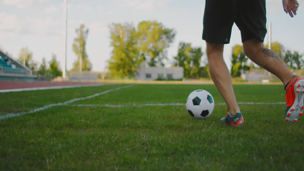 Close up of a male soccer player running with a soccer ball on the football field in the stadium demonstrating excellent dribbling