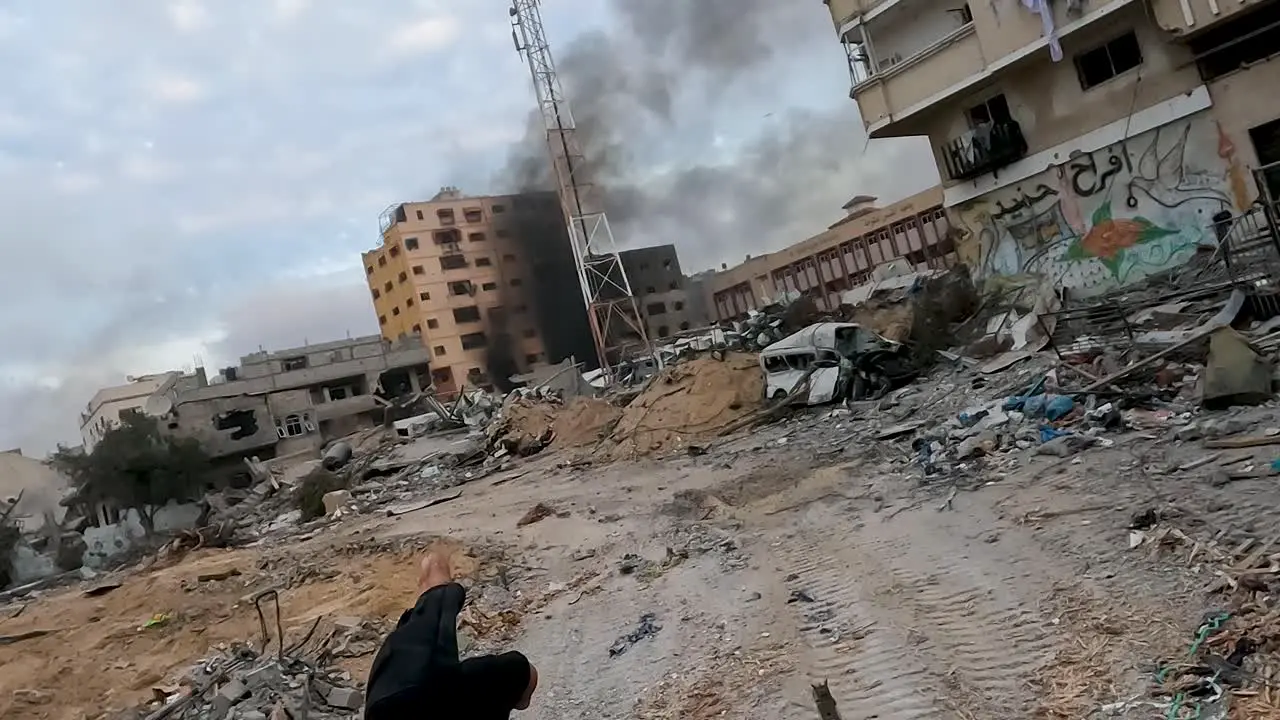 Bombed city with buildings on fire in Gaza hand pointing at destroyed buildings