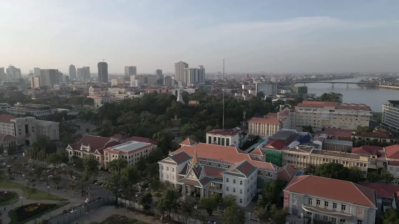 Low aerial pan over river city buildings of Phnom Penh Cambodia