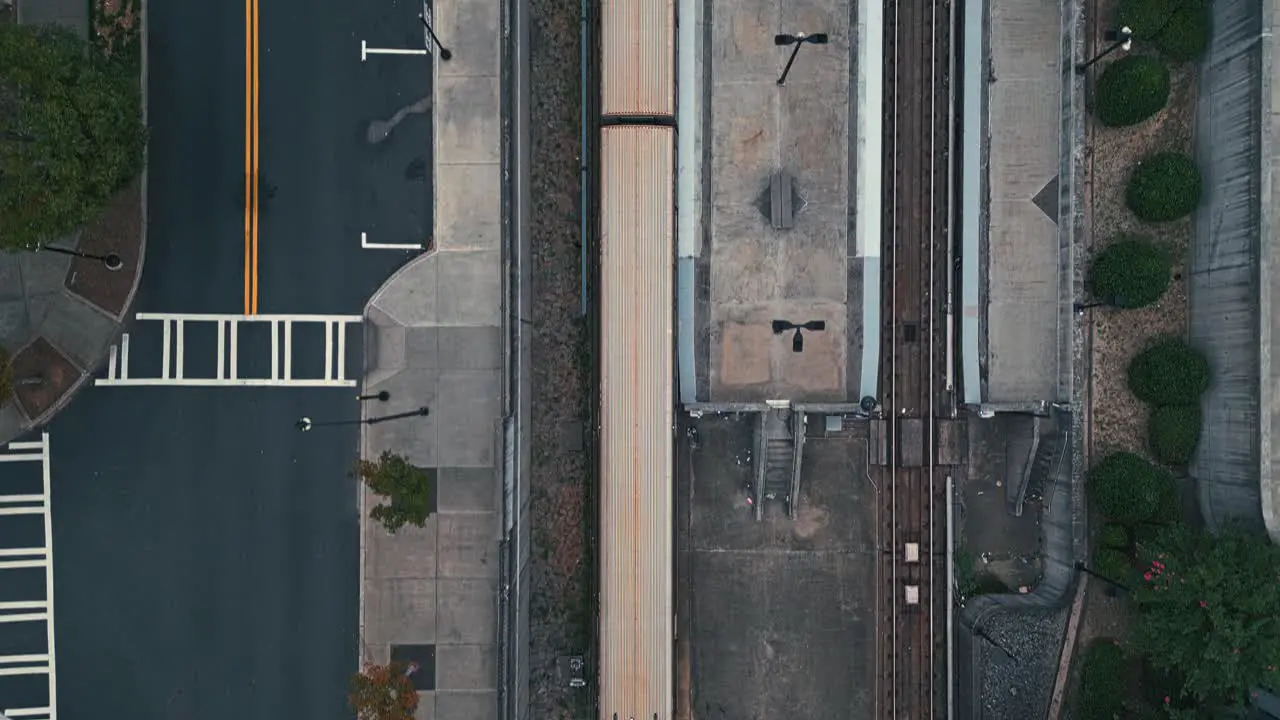 Aerial top down shot of train riding on rail in city of Atlanta with cars in road during cloudy day