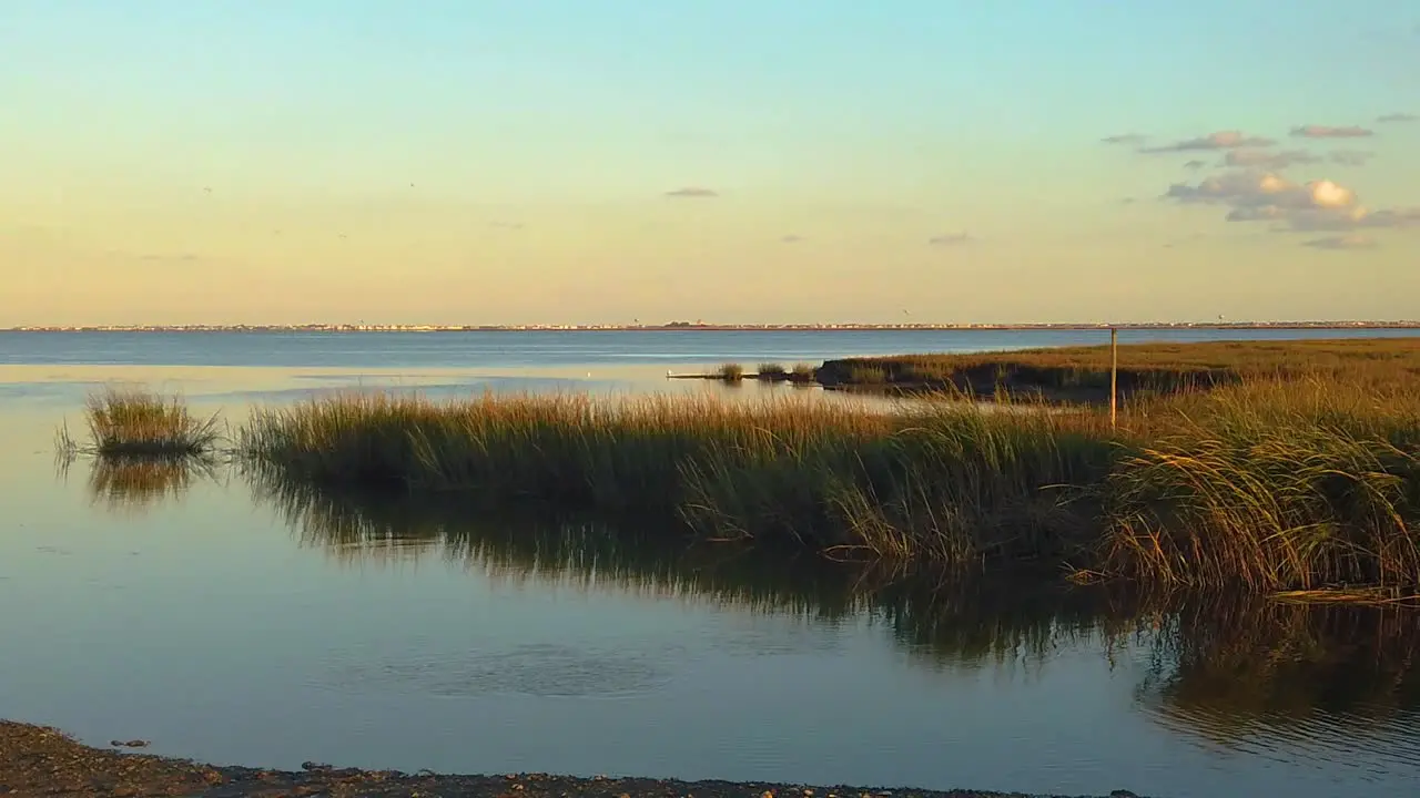 HD 120 fps pan left to right from waterway view with tall grass to reveal Atlantic City skyline in distance with mostly clear sky near golden hour