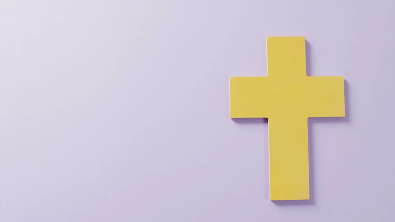 Video of yellow christian crucifix cross symbol on lilac background with copy space