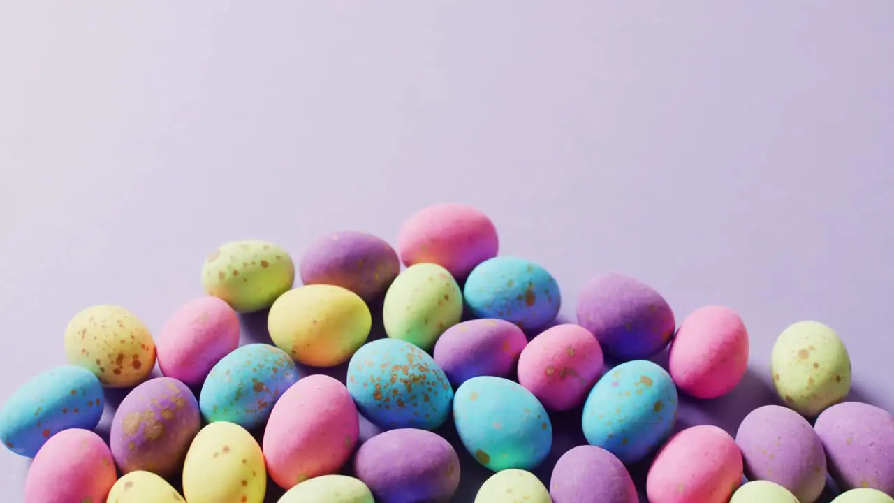 Multiple colorful easter eggs on purple background with copy space