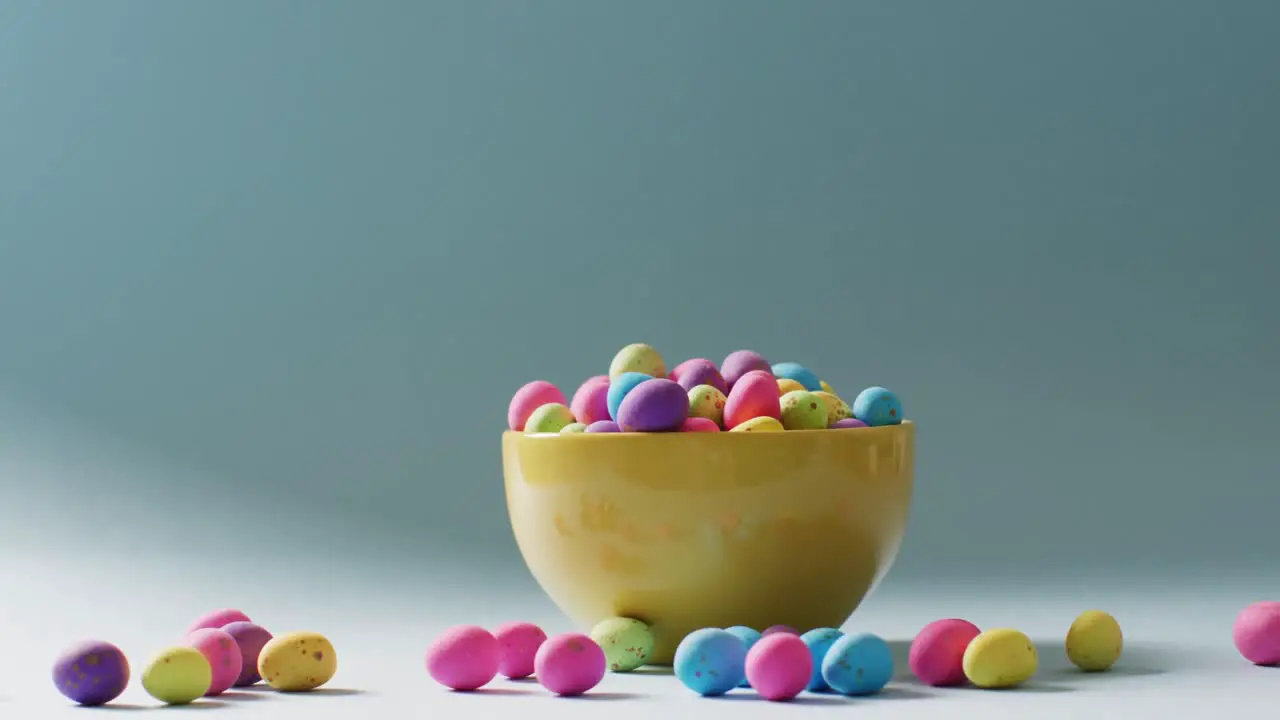 Bowl with colorful easter eggs on green background with copy space