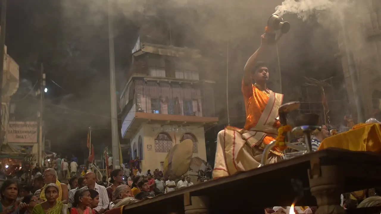 Man Waves Incense and Rings Bell before a Crowd