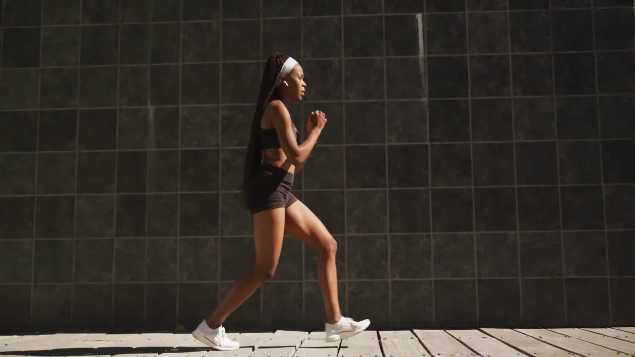 African american woman exercising outdoors wearing wireless earphones stretching in the city