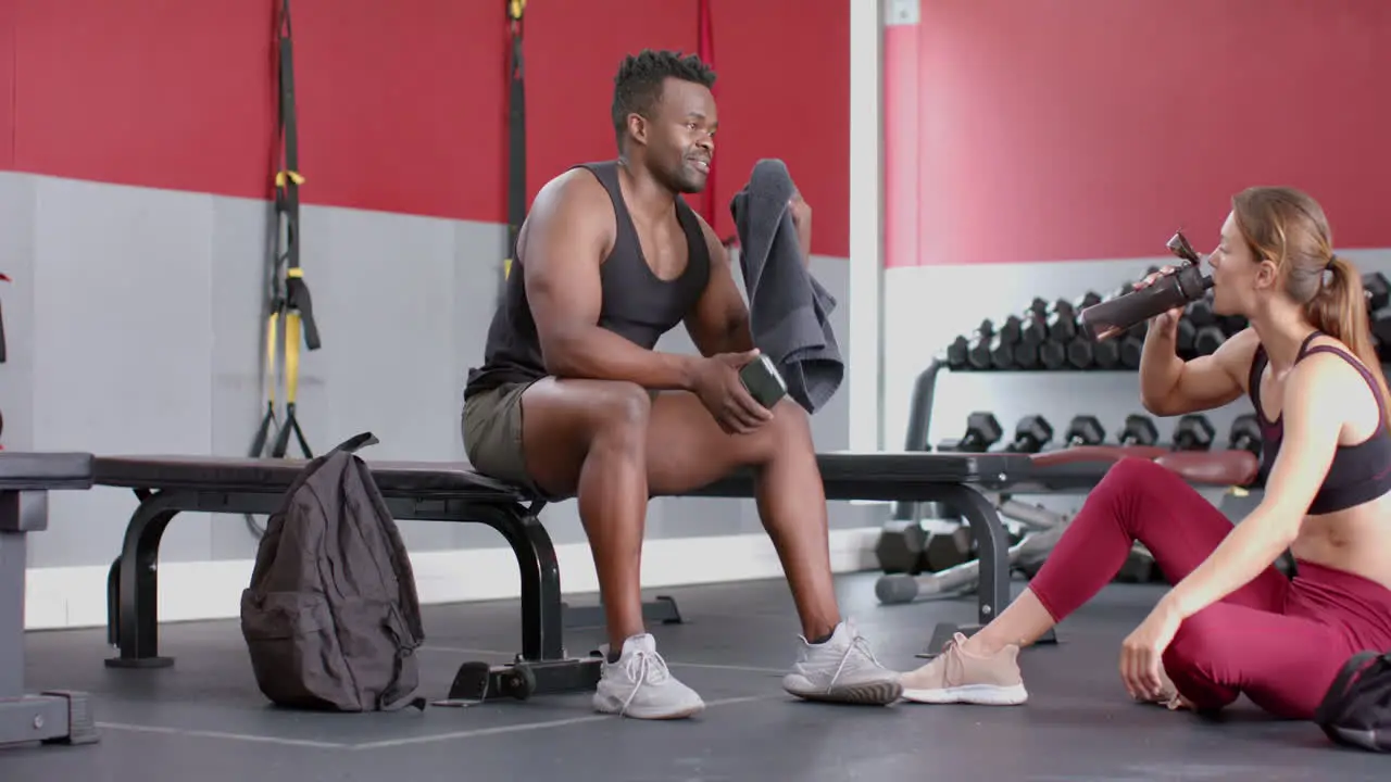 Fit African American man and young Caucasian woman rest at the gym