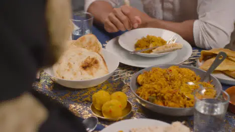 Close Up Of Muslim Muslim Family Sitting Around Table At Home Eating Meal To Celebrate Eid 1