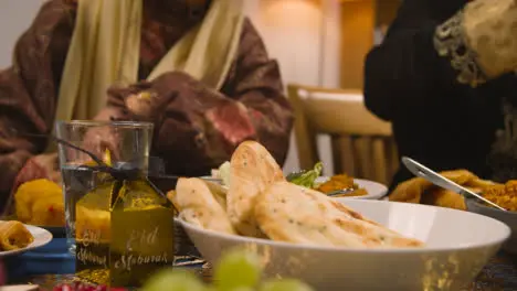 Muslim Mother And Daughter Eating Around Table At Home Celebrating Eid