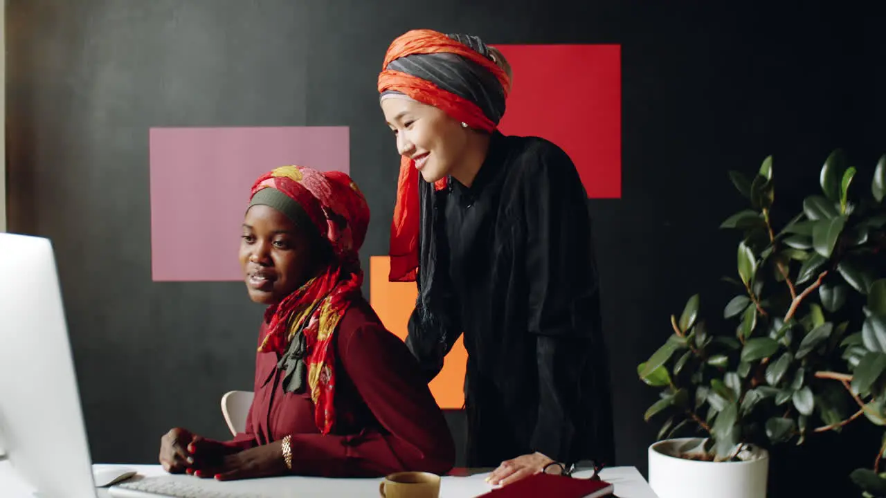 Female Muslim Coworkers Working at Desk